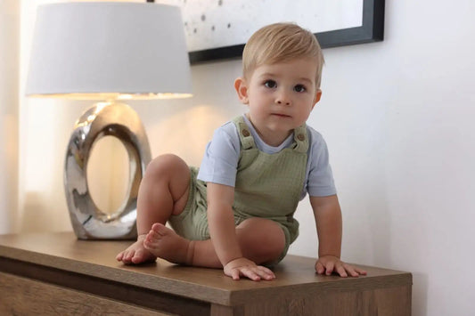 Enfant garçon en salopette gaufrée verte et t-shirt bleu à la maison