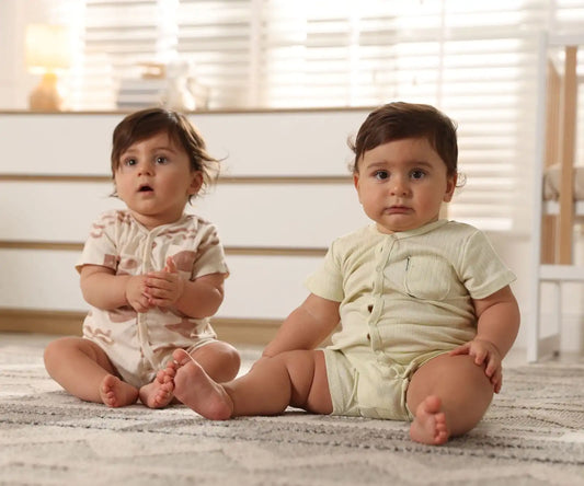 Deux bébés assis sur un tapis dans une chambre lumineuse en tenues assorties
