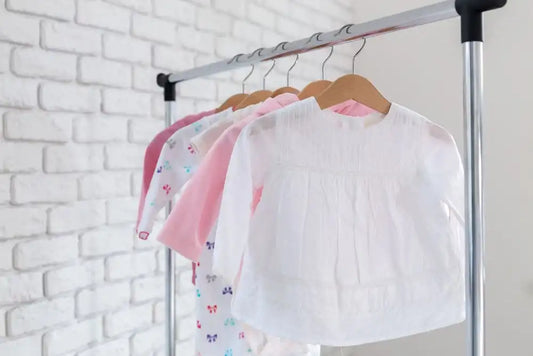 Hauts bébé en coton rose suspendus sur un portant de vêtements