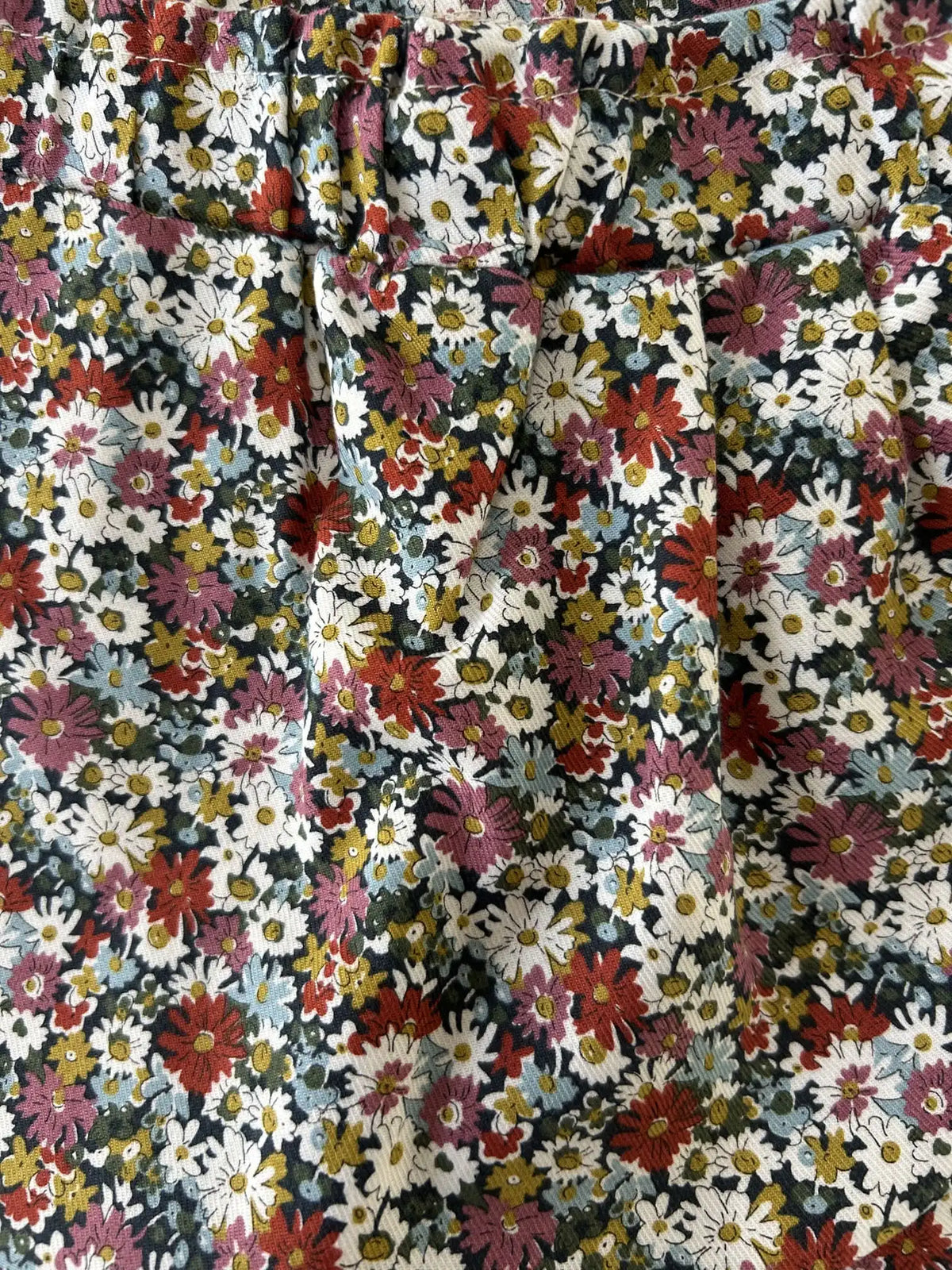 Gros plan sur le tissu Liberty fleuri marine et les plis de la jupe-culotte bébé fille