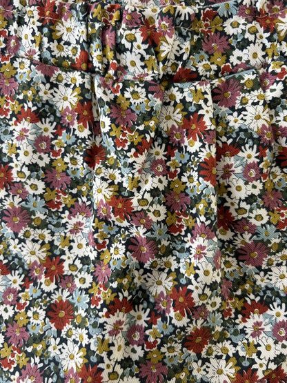 Gros plan sur le tissu Liberty fleuri marine et les plis de la jupe-culotte bébé fille