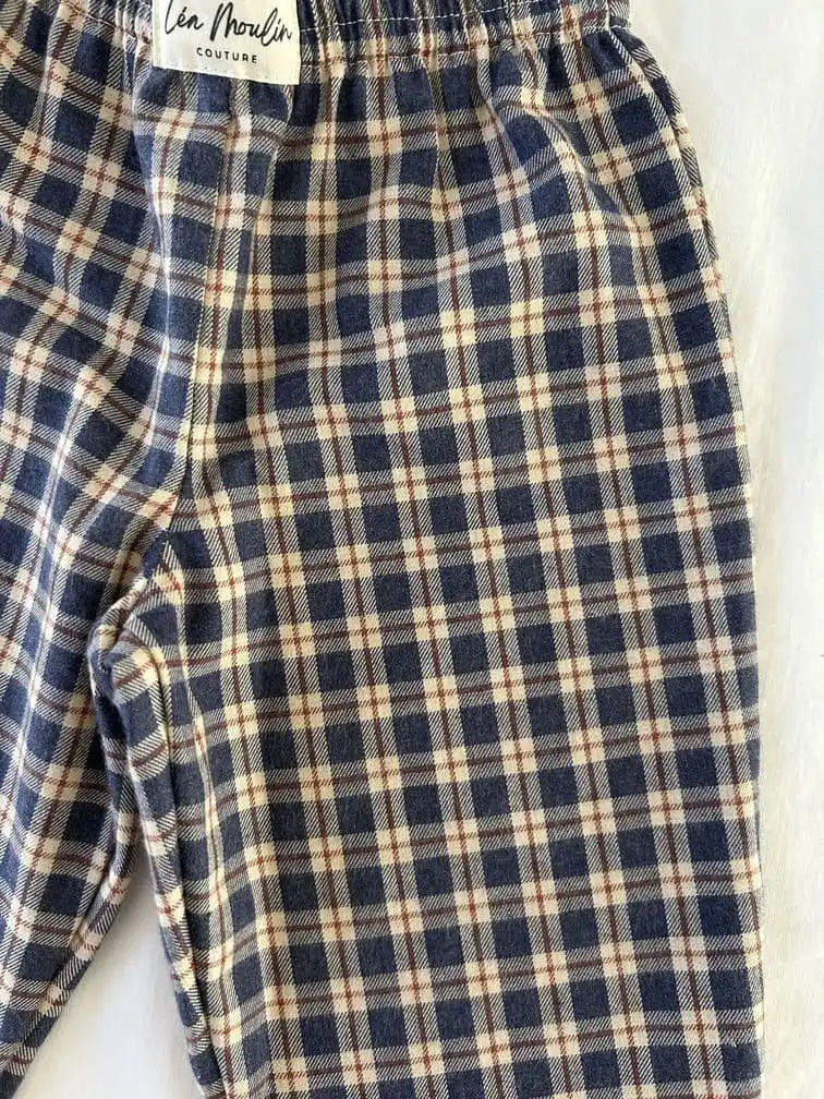 Taille élastiquée et étiquette Léa Moulin Couture d'un pantalon à carreaux bleu marine et écru, vue de près