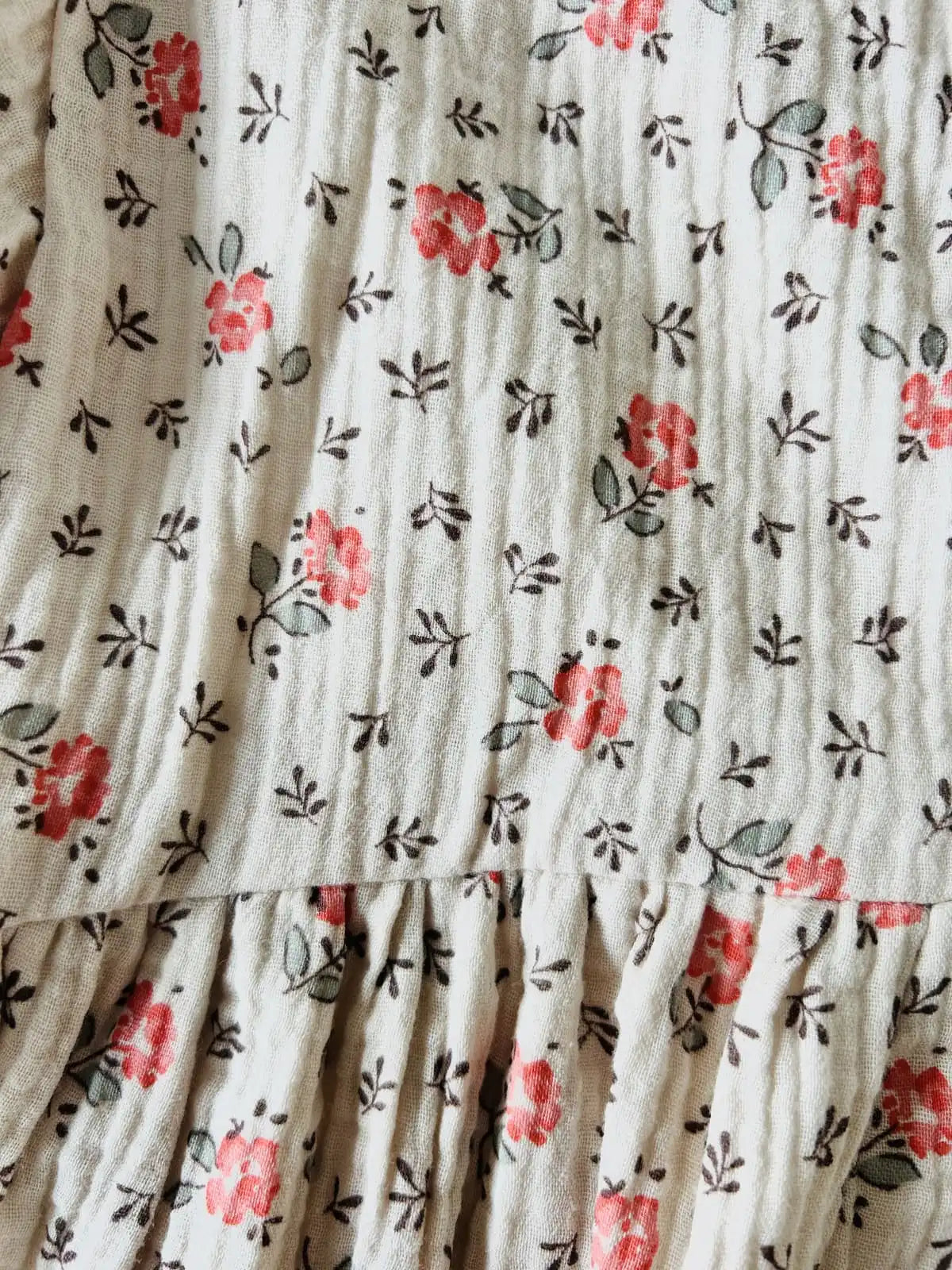 Détail du tissu gaze de coton fleuri crème et rose de la robe bébé Capucine