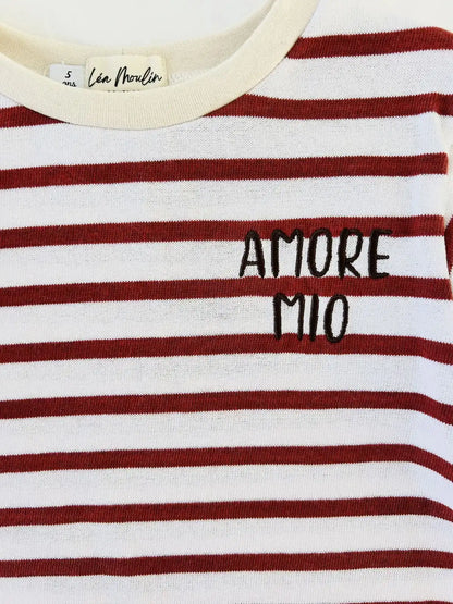 Gros plan sur la broderie noire Amore Mio et le col rond d'un sweat rayé rouge