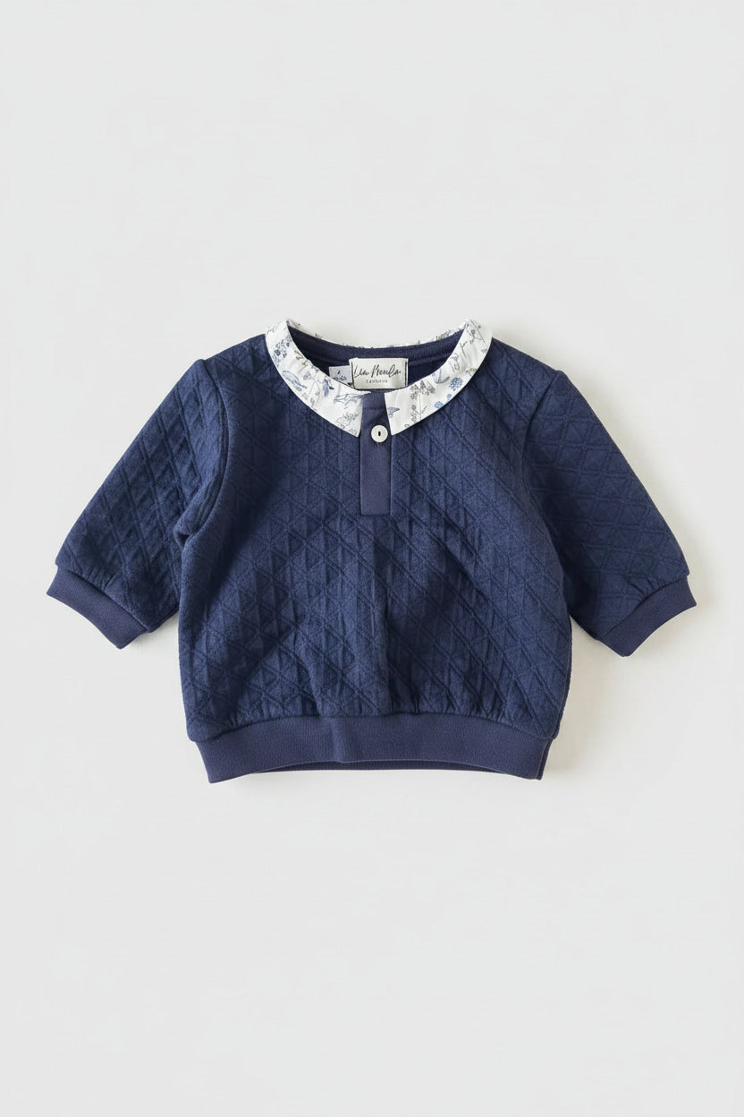 Détail du col en tissu Liberty et bouton unique sur encolure de l'ensemble en coton bleu.