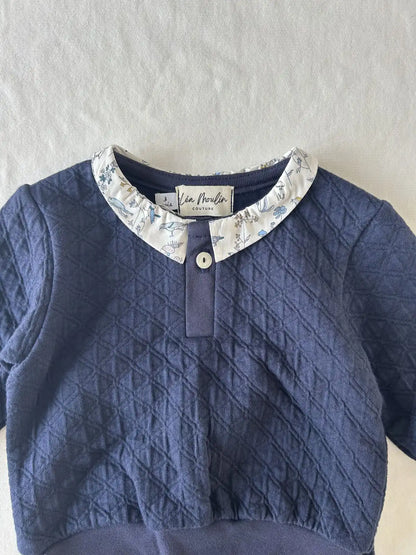 Détail du col en tissu Liberty et bouton unique sur encolure de l'ensemble en coton bleu.
