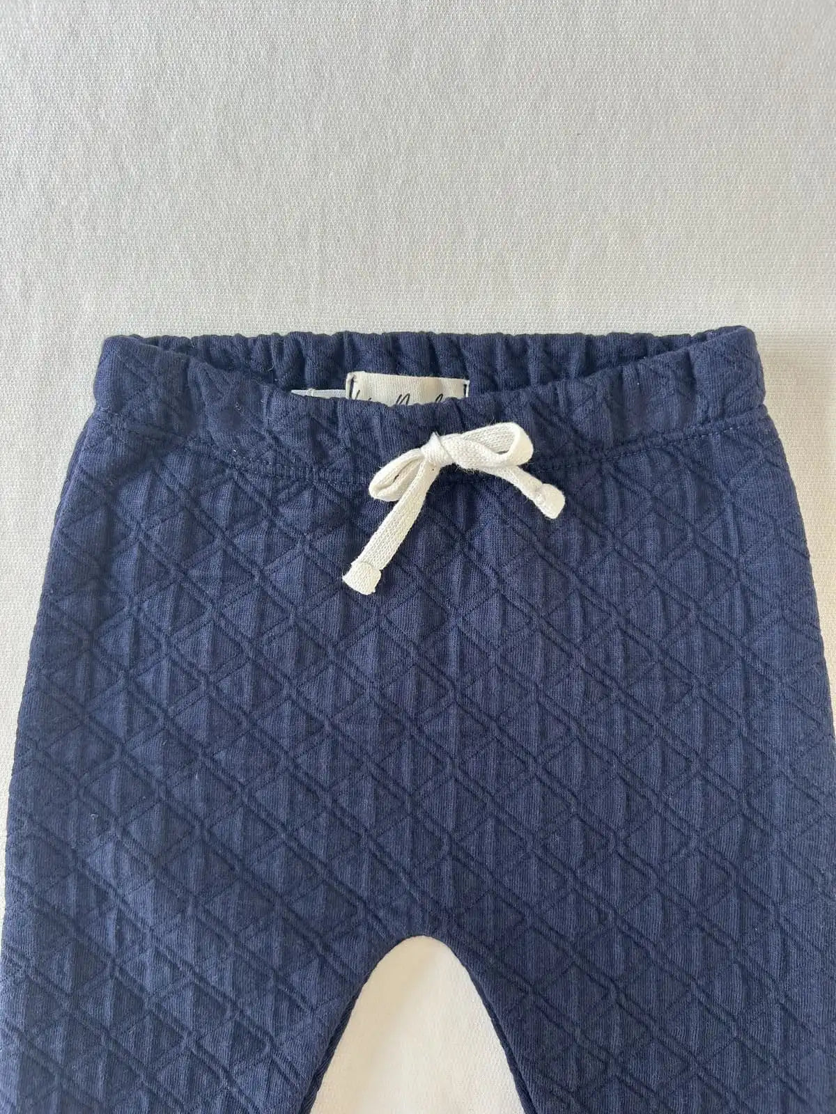 Zoom sur la taille élastiquée avec lien décoratif blanc du pantalon bébé en coton matelassé