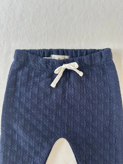 Zoom sur la taille élastiquée avec lien décoratif blanc du pantalon bébé en coton matelassé