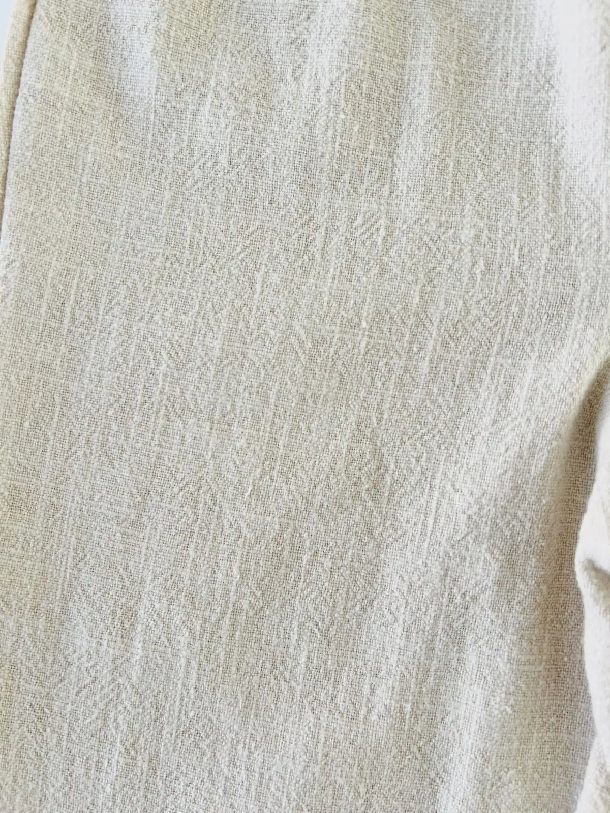Gros plan sur le tissu tissé en lin et coton beige chiné du pantalon bébé Ernest