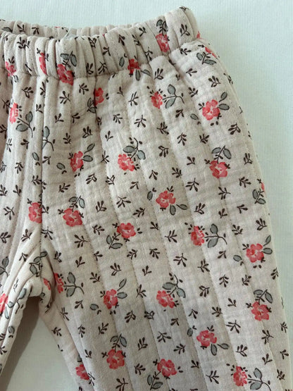 Gros plan sur le tissu matelassé du pantalon bébé Garance, imprimé fleuri rose et corail sur fond écru