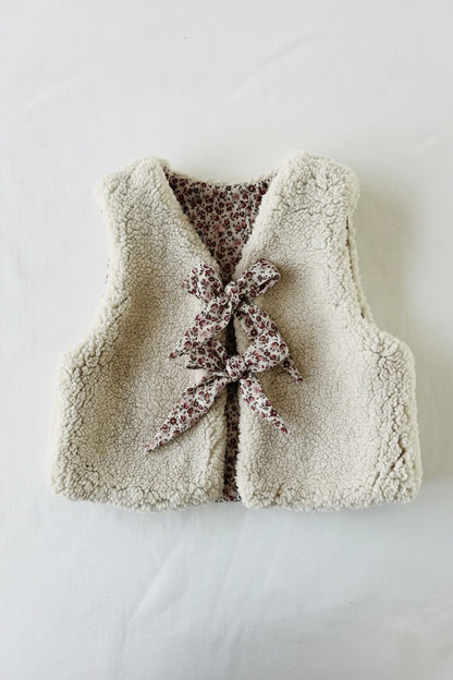 Gilet bébé réversible vu de dos côté sherpa écru moelleux avec nœud fleuri