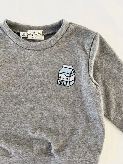 Gros plan sur la broderie brique de lait bleu clair sur le sweat gris chiné
