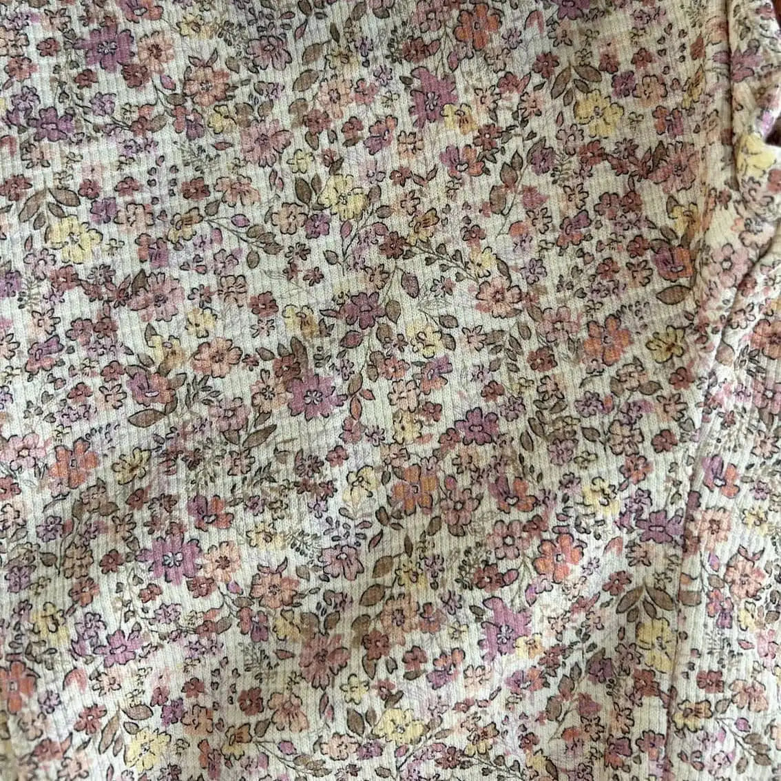 Gros plan sur le tissu gaufré fleuri rose et écru du pantalon bébé fille Louise