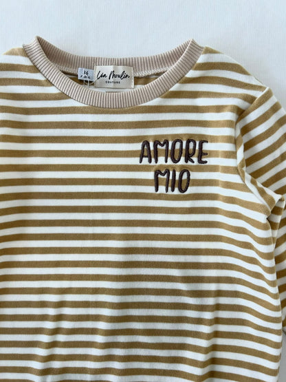 Gros plan sur la broderie Amore Mio et l'encolure extensible d'un sweat bébé rayé jaune moutarde