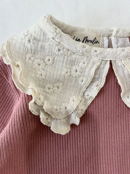 Gros plan sur le col brodé fleuri en gaze de coton d'un pull bébé fille vieux rose, fait main Léa Moulin Couture