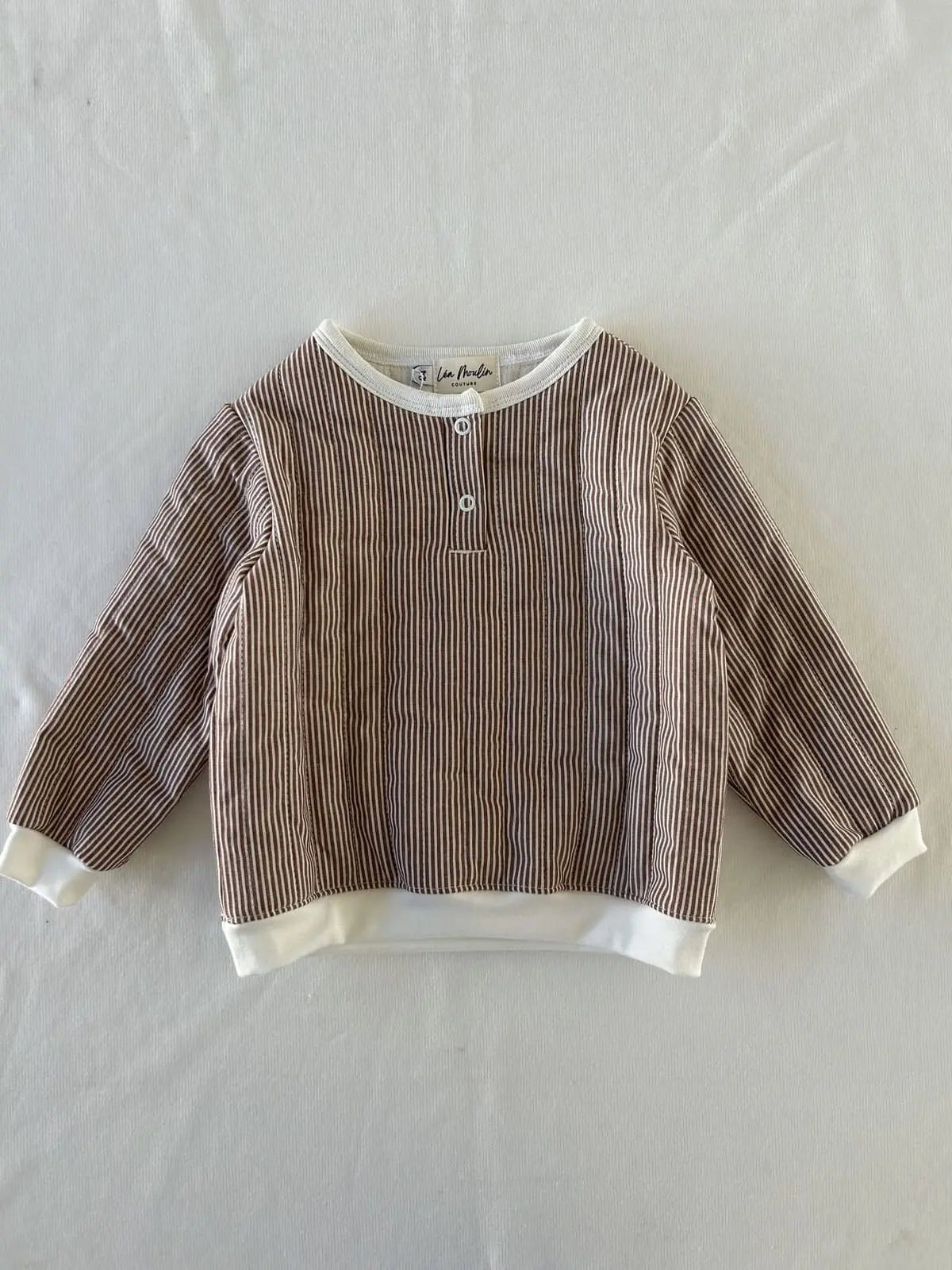 Détail pressions et bord-côte sur sweat bébé rayé.