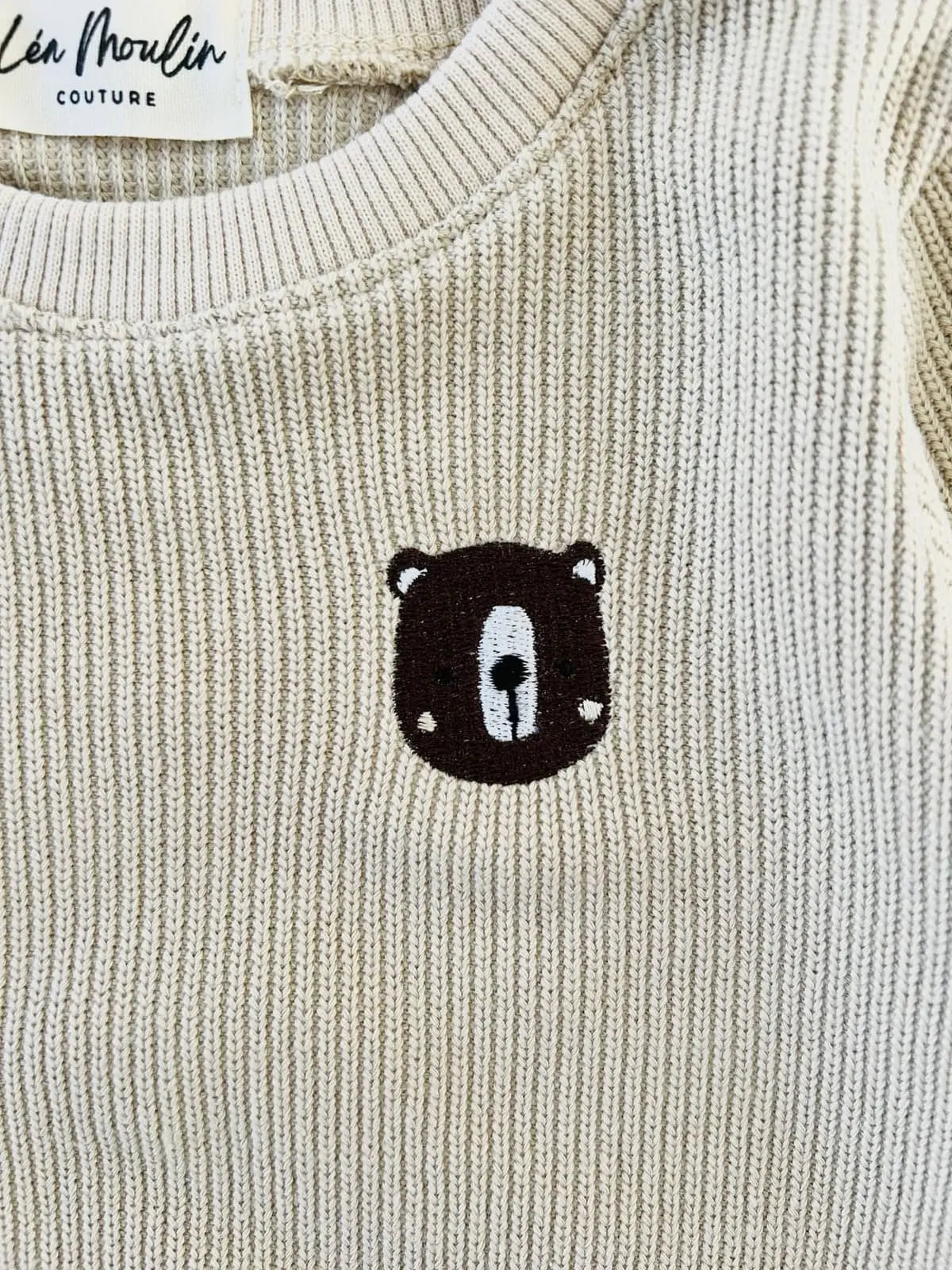 Détail broderie tête d'ours faite main sur maille côtelée.