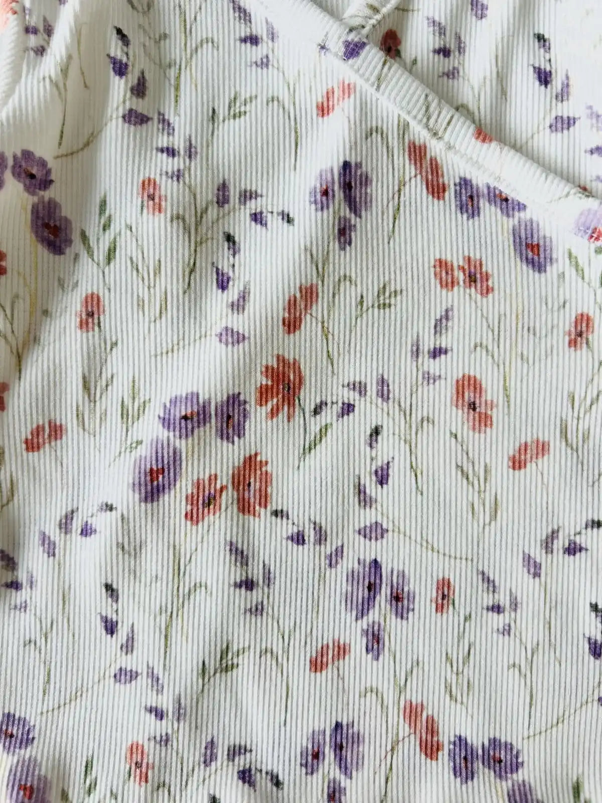 Détail maille côtelée coton sur brassière bébé fille motif fleur.